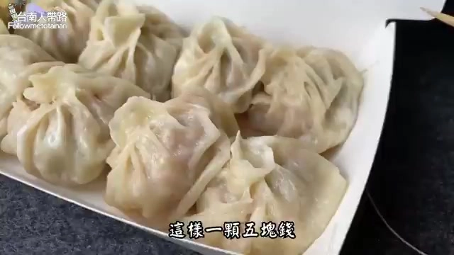 白色紙盒中盛裝多顆小籠包，皮薄透亮，摺紋精緻，標示「這樣一顆五塊錢」