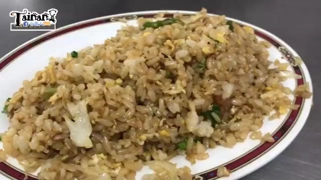 白色瓷盤盛著炒飯，米粒粒粒分明，夾雜蛋花與蔥花，邊緣有紅色描邊裝飾