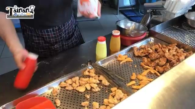 店員在不鏽鋼餐檯上準備裝袋的炸物,一旁擺著調味醬料瓶