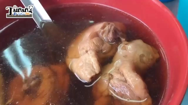 紅色碗中盛著粿仔雞湯，可見完整的雞腿肉塊，湯色深褐濃郁