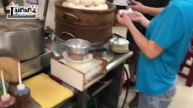 蒸籠冒著熱氣，可見層層堆疊的白胖包子，員工正在旁邊整理餐具與配料瓶