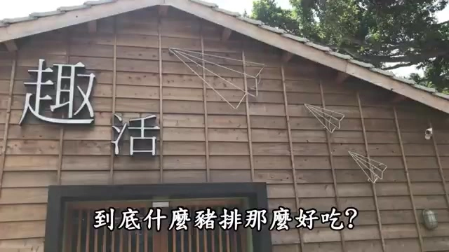 木造建築外牆，白色立體字寫著「趣活」，屋簷下掛著紙飛機造型裝飾，字幕寫著「到底什麼豬排那麼好吃?」