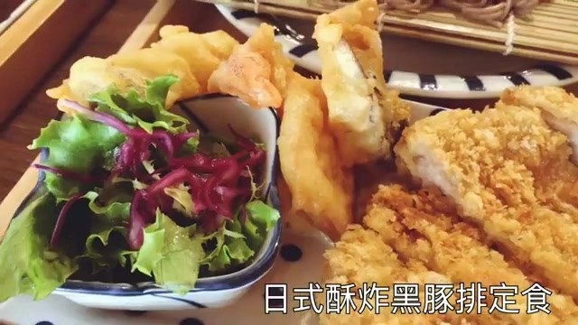 白色瓷盤盛著日式酥炸黑豚排定食，可見金黃酥炸豬排、天婦羅與生菜沙拉，字幕寫著「日式酥炸黑豚排定食」