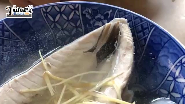 藍白瓷碗盛著虱目魚肚湯，魚肚肉質白皙搭配薑絲，湯色清澈
