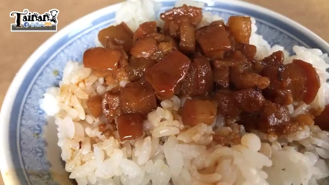 白色瓷碗盛著肉燥飯，深色滷肉丁淋滿米飯，油亮誘人