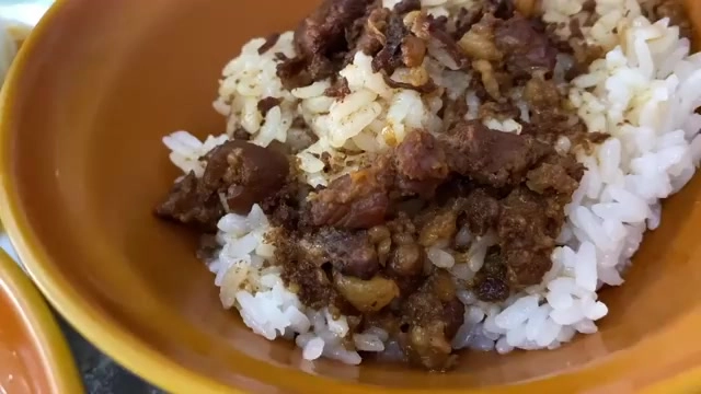 橘色碗中盛著白飯,上頭鋪滿深色滷肉燥,油亮誘人