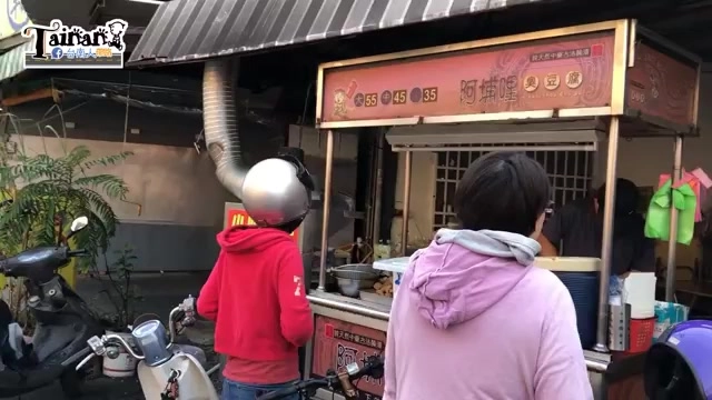 路邊攤販賣攤位掛著紅底招牌，上面寫著「阿埔哩臭豆腐」與價位標示，排隊人潮眾多