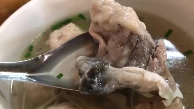 湯匙舀起魚丸與魚皮，湯色清澈撒著蔥花