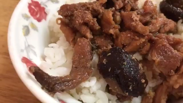 特寫香菇肉飯，深色滷肉與香菇鋪在白飯上，醬汁色澤濃郁
