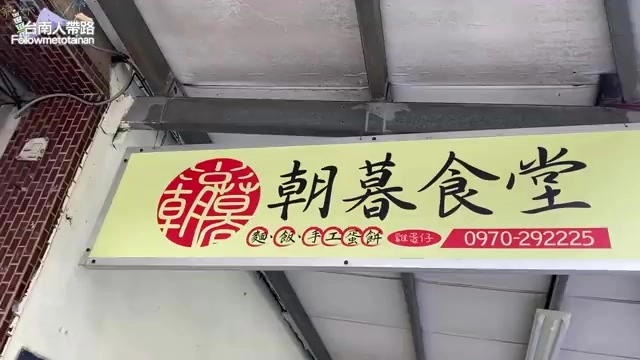 黃色招牌上寫著「朝暮食堂」，標示麵、飯、手工蔥餅字樣與電話號碼