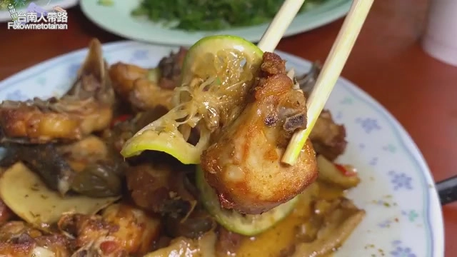 淋著薑黃醬汁的雞肉塊,搭配檸檬片與蔥花,色澤金黃油亮