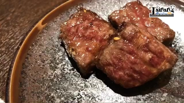 黑色石板上盛著三塊烤牛小排,表面焦香帶油花光澤,切面可見粉紅肉色