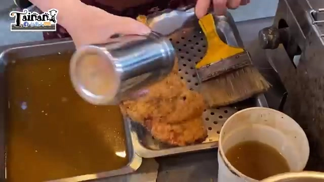 師傅正將醬汁淋在剛炸好的雞排上,一旁刷子準備均勻塗抹