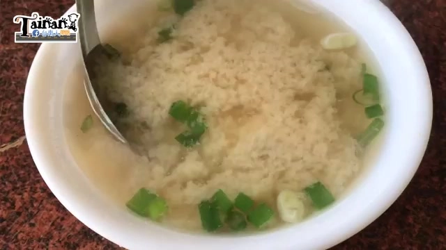 白色瓷碗盛著味噌魚湯，湯色乳白帶淡黃，撒上蔥花點綴