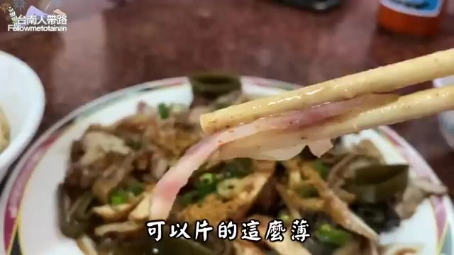 筷子夾起薄切的粉紅色豬耳朵片，搭配蔥花與辣椒