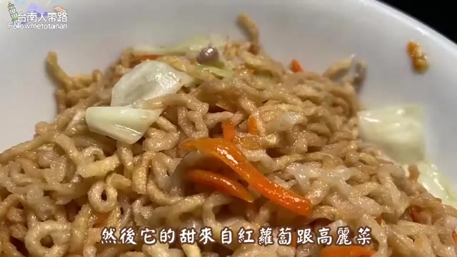 白色瓷碗中盛著淡色乾意麵,夾雜紅蘿蔔絲與高麗菜,麵條清爽不帶濃重醬色