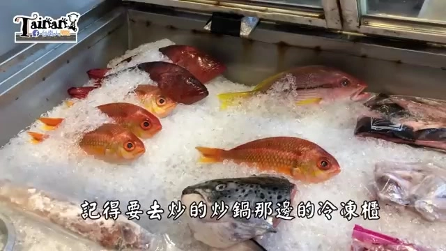 冷凍展示櫃裡擺滿新鮮魚貨,鋪在碎冰上,包含多條紅色與黃色魚身的鮮魚