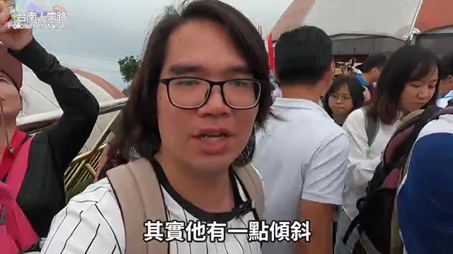 阿波走在人潮擁擠的佛手橋上，向鏡頭解說佛手雕塑的傾斜角度
