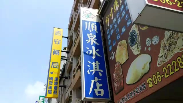 直立招牌，藍底白字寫著「順泉冰淇店」，一旁緊鄰藥局招牌