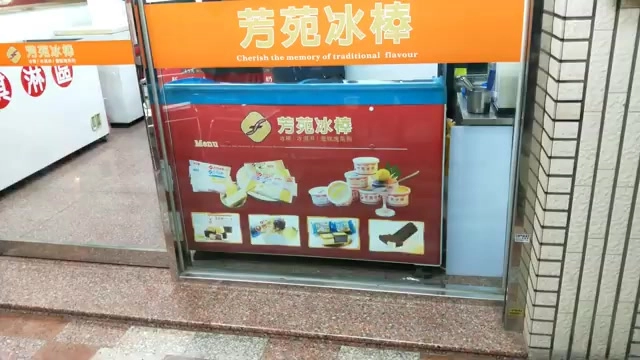 橘色招牌上寫著「芳苑冰棒」與「Cherish the memory of traditional flavour」，下方冰櫃展示多種冰品照片與菜單
