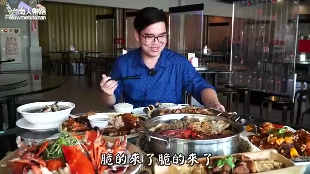 阿波夾起茶油煎雞，展示乾酥雞皮口感