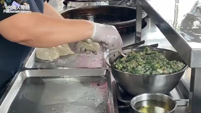 店員戴著手套將翠綠色的蔥餡放入麵皮中,一旁鋼盆裝著滿滿的內餡料